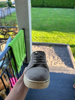 Gråa lubbs sneakers i mocka - Snygga grå loubtin i mocka med vita sulor och matchande grå skosnören. Klassisk låg modell som passar till det mesta och ger en clean look. Perfekt för dig som gillar stilrena och enkla skor. Köpt från deras egen hemsida för 6000kr, säljer dom för använder det inte längre men kan byta dom mot lanvins också.