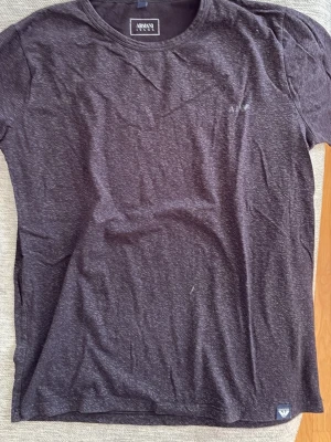 Mörkgrå t-shirt från Armani Jeans - Snygg mörkgrå t-shirt från Armani Jeans med diskret logga på bröstet. Klassisk rund halsringning och korta ärmar. Materialet känns mjukt och bekvämt, perfekt för en avslappnad stil.