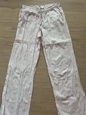 Rosa linnebyxor från Gina tricot - Säljer ett par rosa linnebyxor med snören där fram och fickor där bak. (Dessa finns ej kvar i butik).