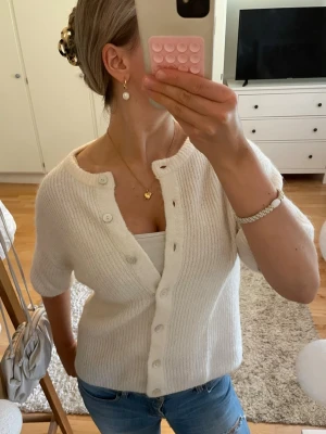 Vit ribbad kofta med kort ärm - Så snygg vit kofta i ribbstickat material med korta ärmar och rund hals. Koftan har knappar framtill och en avslappnad passform. Använd 1-2 gånger!! 🫶🏼🫶🏼