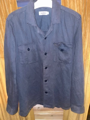 Mörkblå overshirt ( Dressman ) - Overshirt i mörkblått med två bröstfickor med lock och knappar. Klassisk skjortkrage, långa ärmar och knäppning framtill. Tillverkad i ett mjukt tyg som ger en avslappnad vibe och passar perfekt som lager.