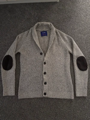 Grå Cardigan men armbågslappar - Tjenare, säljer en fet ljusgrå Cardigan men armbågslappar den e otroligt snygg o sitter väldigt bra på mig som är 185 o väger runt 59-60 kg. Skriv vid minsta lilla fråga