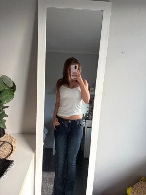 Mörkblå bootcut jeans - Snygga mörkblå bootcut jeans med låg midja och klassiska fem fickor från true religion. Jeansen har lätt slitning framtill och vida ben som ger en retro vibe. Perfekta för dig som gillar en avslappnad men trendig stil. 