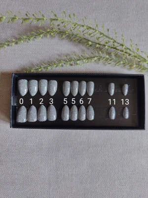 Switch Nails Silver Flash press-on naglar - Snygga press-on naglar i silver med glittereffekt. Naglarna har en elegant mandelform och kommer i flera storlekar för perfekt passform. Materialet är plast och ytan är slät och glansig för en trendig look. Säljer överblivna oanvända storlekar. Inga tillbehör 