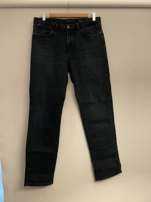 Svarta raka jeans - Snygga riktigt mörkblå jeans med rak passform och klassisk femficksdesign. Jeansen har normal midja och stängs med knapp och dragkedja. Materialet ser ut att vara denim med lätt stretch för extra komfort. Perfekta till en avslappnad stil.