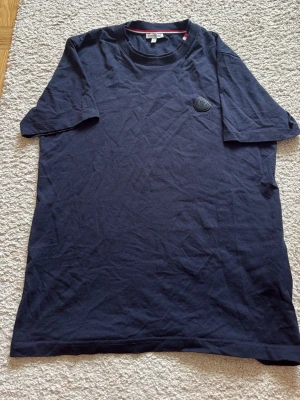 Mörkblå Moncler t-shirt i bomull - Snygg mörkblå t-shirt från Moncler med klassisk rund hals och korta ärmar. T-shirten har Monclers logotyp på bröstet och är tillverkad i mjuk bomull för en bekväm känsla. Perfekt till jeans eller shorts för en clean look.