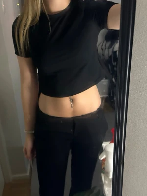 Svart croppad t-shirt - En enkel svart croppad t-shirt med rund hals och korta ärmar. Perfekt till jeans eller kjol för en avslappnad och trendig look. Materialet känns mjukt och stretchigt, troligen bomull eller en bomullsblandning.
