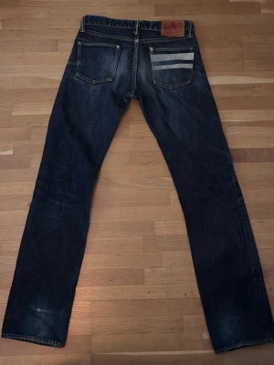 Momotaro GTB selvedge - Säljer ett par mörkblå momotaro jeans med raka ben och klassisk femficksmodell. Jeansen har slitningar för en avslappnad look och är tillverkade i selvedge denim. Inte använda av mig då dom inte passar, Mått finns på bilderna👍
