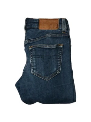 Tiger Of Sweden Mörkblåa Jeans - Snygga mörkblå jeans med klassisk femficksdesign och raka ben. Jeansen har en brun läderpatch i midjan och kontrastsömmar. Perfekta för en avslappnad och trendig look. Tillverkade i denim med en skön passform. W28 L32