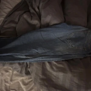 Blå jeans från Calvin Klein - Snygga blå jeans från Calvin Klein med klassisk femficksdesign och brunt läderpatch bak. Jeansen har raka ben och är tillverkade i slitstarkt denimtyg med tydliga sömmar och metallknapp med logga. Vet inte exakt storlek men tror de är en S 