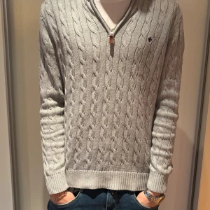 Grå kabelstickad tröja halt zip från Morris  - Snygg grå kabelstickad tröja med half zip från Morris. Tröjan är i ett fint skick med inga defekter! Vid funderingar är det bara att höra av dig!