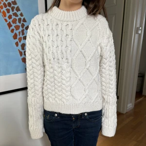 Vit stickad tröja från H&M XS - Superfin vit stickad tröja från H&M i storlek XS. Tröjan har ett snyggt flätmönster framtill och på ärmarna, samt ribbade muddar och rund hals. Perfekt för kyliga dagar och riktigt mysig att ha på sig.