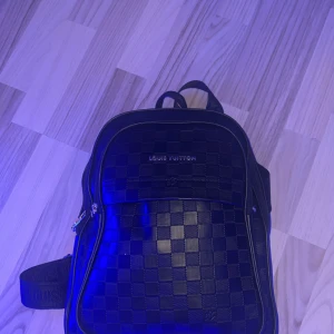  Louis Vuitton ryggsäck - Den har 3 fack, nedersta har ingen dragkedja därför säljer jag den billigt! Snygg svart ryggsäck från Louis Vuitton med klassiskt rutigt mönster och silverfärgade dragkedjor. Väskan har ett stilrent och modernt utseende med justerbara axelremmar och praktisk framficka. Perfekt för dig som vill ha en lyxig och trendig accessoar.