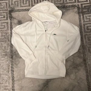Vit hoodie från Lacoste - Zip up hoodie från Lacoste. Lapp medföljer. Storlek M, mer likt en S. Pris kan diskuteras. 
