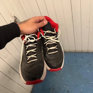 Svarta Nike Air Jordan sneakers - Säljer ett par svarta Nike Air Jordan sneakers med röda detaljer och vit sula. Skorna har klassisk Jumpman-logga på sidan, nummer 23 på hälen och vit snörning. Ovandelen är i skinn och insidan är fodrad i rött tyg. Perfekta för dig som gillar streetstyle.