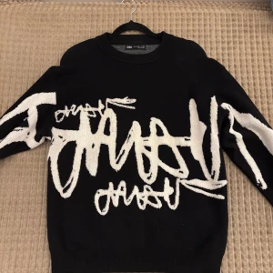 Svart tröja med vit grafisk text Zara - Cool svart tröja från Zara med vit grafisk text och mönster över hela framsidan och ärmarna. Tröjan har rund halsringning och är långärmad. Materialet känns mjukt och passar perfekt för höst och vinter.