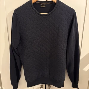 Mörkblå tröja Massimo Dutti - Snygg mörkblå tröja från Massimo Dutti i bomull. Tröjan har quiltat mönster framtill, rund halsringning och långa ärmar. Perfekt för dig som gillar stilrena och bekväma plagg.                         Liten i storleken!