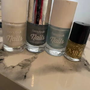 Nagellack i olika färger - Fyra nagellack: ett pärlemorvitt, ett mörkgrått med metallicfinish, ett ljusblått och ett guldglittrigt. Tre från beauty uk och ett från SMILE. Perfekt för att mixa och matcha olika nagellooks.