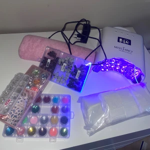 Färgglada glitter och strass till naglar - Säljer ett stort kit med nageldekorationer, inklusive glitter i flera färger som rosa, blå, guld och grönt, strass i olika former och storlekar samt nagelstickers med fjärilar. Perfekt för att skapa kreativa och unika nageldesigner hemma. Det är använt men allt funkar bra