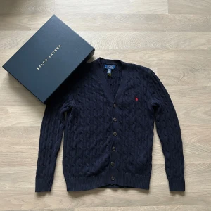 Ralph Lauren Knit Cardigan - Säljer en Ralph Lauren Knit Cardigan i bomull med smal passform. Köpt från barnavdelningen i storlek L (14-16), men passar för XS. Mycket bra skick. Vid köp skickas även originallåda med. Pris kan diskuteras // Hör av dig vid eventuella frågor!
