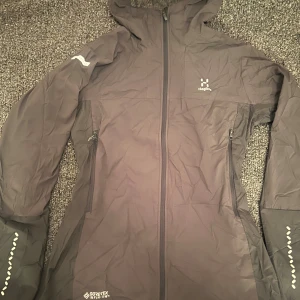 Grå GORE-TEX/Fleece från Haglöfs - Reflexdetaljer på ärmarna och logga på bröstet. Figur sydd storlek M passar även S, bara prövat på 1 gång