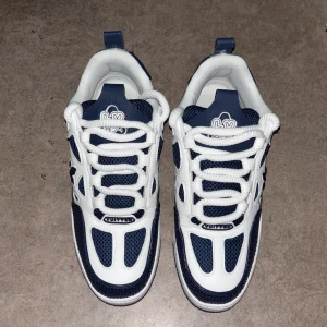 IV skates  - Säljer ett par sneakers i marinblått och vitt med coola detaljer och grafiska mönster på hälen. Skorna har snörning, rund tå och platt sula. Materialet är en mix av skinn och syntet med meshpaneler för extra ventilation. Perfekt för dig som gillar exklusiv streetstyle.