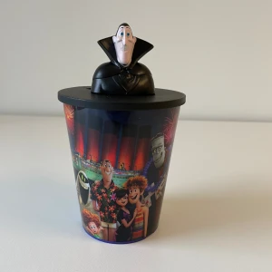 Hotel Transylvania - Glas med lock och sugrörshål i locket för att undvika att få getingar tex i drickan. Hotel Transylvania med färgglada karaktärer och Drac-figur på locket. Glaset är i plast och rymmer ca 3.75 dl. Helt nytt. 