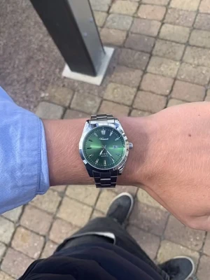 Grön Doventi klocka med metallarmband - Snygg klocka från Doventi med grön urtavla och silverfärgat metallarmband. Urtavlan har stilrena indexmarkeringar och datumvisning. Quartz-urverk och polerad finish ger en modern vibe. Perfekt accessoar för dig som vill sticka ut med en cool detalj.