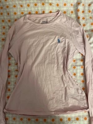 Ljusrosa långärmad tröja Polo Ralph Lauren - Supersnygg ljusrosa långärmad tröja från Polo Ralph Lauren. Klassisk design med rund hals och ikonisk blå broderad logga på bröstet. Tillverkad i mjuk bomull som känns skön mot huden. Perfekt till jeans eller kjol för en clean och fräsch look. Priset kan diskuteras 💕