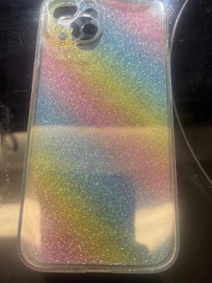 iPhone 15 skal regnbåge glitter - iPhone 15 skal regnbågen färg med glitter. Insidan går att ta bort men är oxå glittrig på sidorna.