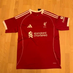 Isak #9 Liverpool - Säljer Liverpool FCs matchtröja med Isak #9. Röd med vita detaljer, kortärmad och i lätt polyester. Liverpool-emblem på bröstet och Nike-logga. Perfekt för Premier League-fans! Följ oss på Instagram: @kickstoreuf
