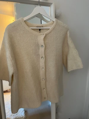 Kortärmad kofta  - Super fin stickad kofta från Gina tricot. Kortärmad med knappar. Säljer pga av fel storlek❤️Vit/beige färg