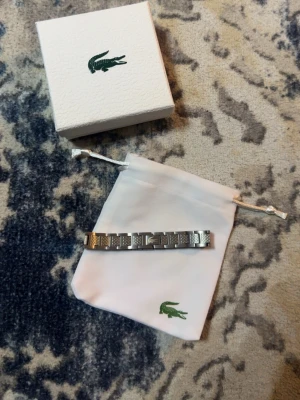 Lacoste armband  - Ett stain less steel Lacoste armband, armbandet är helt nytt och aldrig använt. Det går och göra den mindre om det behövs. Nypris var runt 1,200kr.