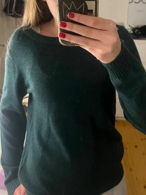 Mörkgrön stickad tröja från Vila - Snygg mörkgrön stickad tröja i storlek S, med rund hals och ribbade muddar vid ärmslut och nederkant. Säljer på grund av aldrig använt