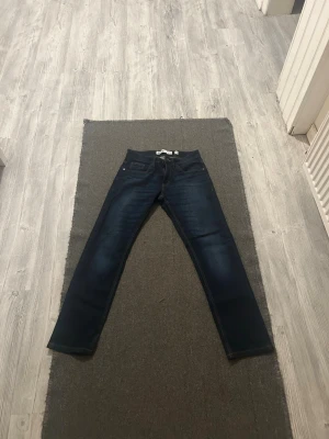 Mörkblå jeans från Indicode, 28/30 - Snygga mörkblå jeans från Indicode med klassisk femficksdesign och kontrastsömmar. Modellen har rak passform och är tillverkad i slitstarkt bomullsmaterial. Perfekt för dig som gillar stilrena och tidlösa jeans med en modern touch. Använts 4 gånger