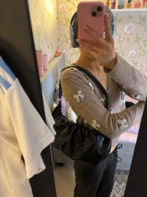 Svart axelväska från Vera moda - Säljer en svart axelväska från Vera Moda med snygg rynkad design och bred axelrem. Väskan är tillverkad i skinnimitation och har metallspännen på remmen. Perfekt storlek för att få plats med allt du behöver och passar till många olika stilar. Den är i helt nytt skick, då den aldrig är använd.