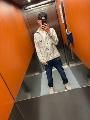 Grå rutig overshirt från Jack & Jones - Säljer en stilren grå overshirt från Jack & Jones med vitt rutmönster. Jackan har två bröstfickor med knappar och klassisk krage. Perfekt att slänga över en t-shirt för en avslappnad look. Tillverkad i mjuk bomull och stängs med knappar framtill. Storlek XS passar på längden 164-170