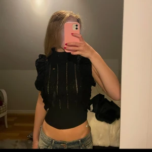 Svart virkad volangtop från Zara - Säljer en svart, croppad virkad topp från Zara. Toppen har flera lager med snygga volanger och spetsdetaljer framtill. Perfekt till alla årstider!💛💛