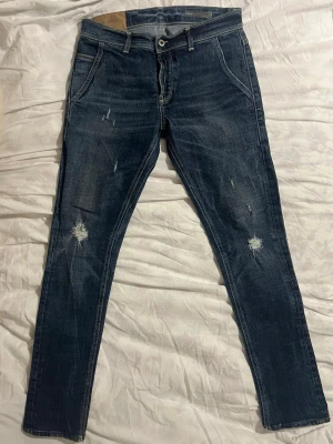 Lite schysstare dondups - Säljer ett par mörkblå jeans från Dondup Jeans med snygga slitningar och detaljerade sömmar. Klassisk femficksmodell med kontrastsömmar och låg midja. Herrejovlars . Längd: 95 cm. 