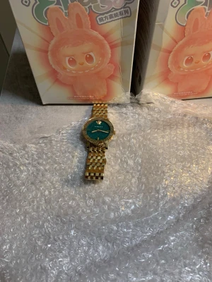  Stilig Classy Versace klocka av guld  med grönt därinne för damer  -  en guldfärgad klocka från Versace med blå urtavla.  Klockan är i mycket fint skick och endast använd 2 gånger fick den i present och kostar ca 15000kr ny 