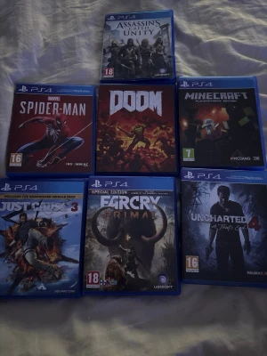 PlayStation 4 spelpaket (7 titlar) - Paket med 7 PS4-spel: Assassin's Creed Unity, Spider-Man, Doom, Minecraft, Just Cause 3, Far Cry Primal och Uncharted 4. Skivorna och fodralen ser ut att vara i gott skick. Perfekt för dig som vill utöka din spelkollektion med populära titlar.