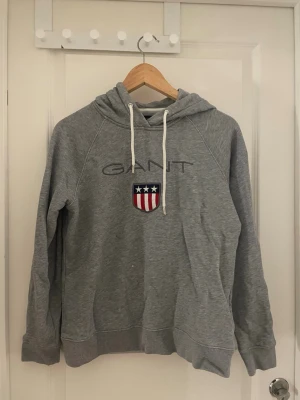 Gant hoodie grå - Gant hoodie har en liten blekt fläck på första bilden så liten att man knappt ser och den ser lite fläckig ut men det är tvättmedel som går bort efter 1 tvätt 