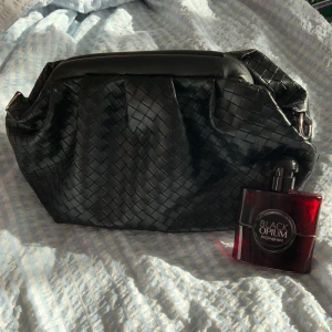 Svart flätad handväska/makeup väska - Snygg svart handväska med flätat mönster. Väskan har en stilren design och är perfekt för att bära med sig det nödvändigaste. Den har en praktisk öppning och är lätt att matcha med olika outfits. Rymmer allt ditt smink och mer! ❤️