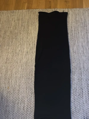 Svart axelbandslös långklänning - Säljer en stilren svart långklänning med axelbandslös design. Klänningen har en rak och tight passform som ger en snygg siluett. 