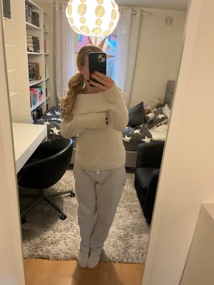 Offshoulder stickad vit tröja - Supermysig offshoulder stickad tröja i vit färg. Tröjan har bred ribbad kant runt axlarna och långa ärmar. Perfekt för dig som gillar en chill och snygg stil med lite extra edge. Passar grymt till jeans eller mjukisbyxor. Skönt nu i kyliga dagar men fortfarande behåller håller stilen!
