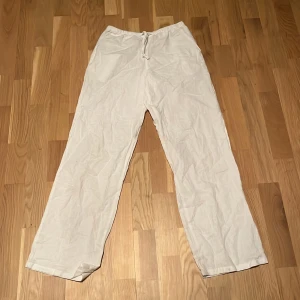 Vita linnebyxor från Gina Tricot - Säljer ett par fräscha vita linnebyxor från Gina Tricot i storlek 146/152. Byxorna har rak passform, elastisk midja med snörning och är tillverkade i mjukt linne. Perfekta för chill dagar och sommarhäng.