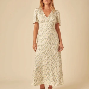 Blommig midiklänning - Superfin midiklänning i ljus bas med små gula och gröna blommor, Klänningen har snörning i midjan, så den kan justeras enligt önskemål. Den är oöppnad från orginalförpackning, säljs då jag köpte två i olika strl. Nypris 989kr. Strl 38, petite. Passar alla i strl 36/38/S men är något kortare än en långklänning.