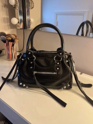 Svart handväska  - Svart cool handväska, ärvt den och vet ej vart den är köpt, lite svart färg framtill på dragkedjan (syns på bild) annars toppskick och inga defekter💘