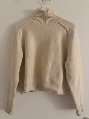 Beige polotröja med ribbad krage - Säljer min beige stickade polotröja med ribbad krage och muddar. Tröjan är från H&M och använd ett fåtal gånger. 