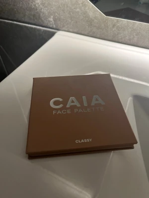 CAIA Face Palette Classy - Snygg ansiktspalett från CAIA i färgen Classy med fyra olika puderprodukter: contour i matt brun, blush i varm rosa, bronzer i gyllenbrun och highlighter i skimrande champagne. Paletten är fyrkantig och har spegel i locket, perfekt för att skapa en fräsch look. Är endast testad.